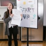 Young woman presenting fundraising charts during a startup pitch, showcasing how storytelling and visuals drive investor engagement.