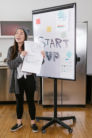Young woman presenting fundraising charts during a startup pitch, showcasing how storytelling and visuals drive investor engagement.