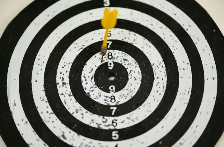 A yellow dart hitting the bullseye on a black and white target, symbolizing precise funding goals set with crowdfunding benchmarks.