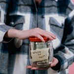 Person holding a savings jar with cash, representing a clear funding goal for saving and financial focus.