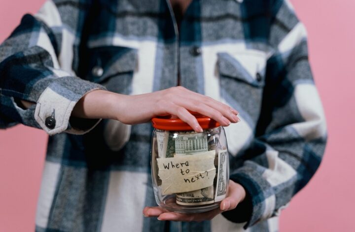 Person holding a savings jar with cash, representing a clear funding goal for saving and financial focus.